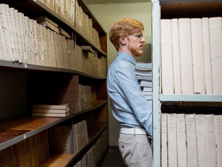 Un agent dans une salle d'archives, les bras chargés de dossiers